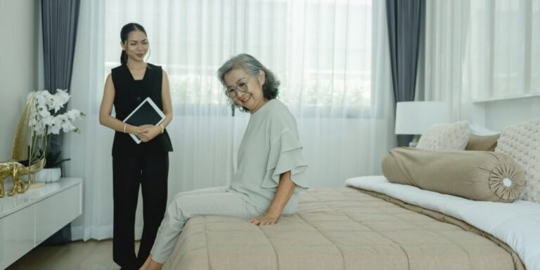 Staff Showing Senior Woman Bedroom Layout in Apartment at Assisted Living Facility