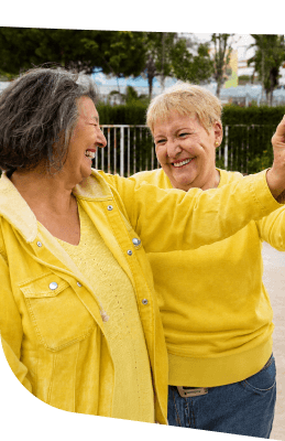 Two Elderly Women in Yellow Dancing Joyfully Outdoors at an Independent Living Community Two Elderly Women in Yellow Dancing Joyfully Outdoors at an Independent Living Community