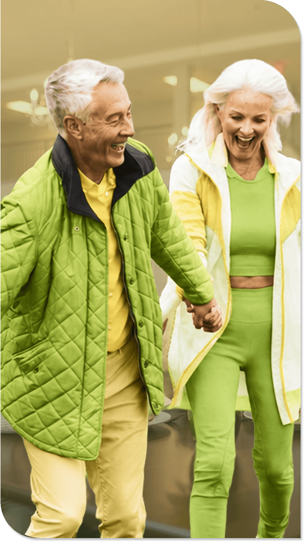 Elderly Couple Laughing and Holding Hands While Walking in Independent Living Facility Elderly Couple Laughing and Holding Hands While Walking in Independent Living Facility